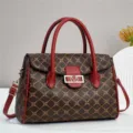 Gedetailleerd overzicht van de bruine monogram handtas met opvallende rode leren handvatten. - Rood