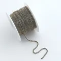 Bunte Strass-Klauenkette Detailansicht mit glitzernden Kristallen auf weißer Spule für DIY Handarbeit. - Fluoreszierendes Kristallgelb AB
