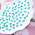 Vista di dettaglio di strass di cristallo a rombi verdi brillanti su un piatto a conchiglia. - 10*6 mm 100 pz/confezione / Blu forato