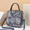 Close-up detail van een stijlvolle vierkante schoudertas met bloemenprint en handvat design. - 18x8x19 / Blauw