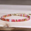 Retro etnische Tila-kraalarmband met roze en gouden accenten op houten oppervlak. - Roze Goud Rood Tila Stijl (Tila 29)