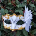 Exquisite weiße Maske für Maskerade mit Goldglanz und eleganten Federn für die Party. - Einheitsgröße / Weiß
