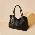 Borsa a spalla nera in pelle con dettagli dorati e ciondolo chic per uso quotidiano. - Nero