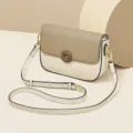 Chic two-tone women's leather crossbody saddle bag with adjustable strap and stylish flap closure. - White
