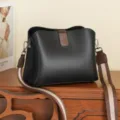 Elegante borsa a secchiello in pelle nera con tracolla stilizzata per uso quotidiano. - Nero