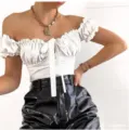 Detail shot of a stylish white off-shoulder short sleeve top with ruffle trim and bow tie. - S / Jumpsuits / White