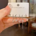 Primo piano dettagliato di un set di orecchini in zircone con ciondoli a stella e croce. - Set di Orecchini Stella e Croce / Argento