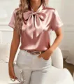 Detailed view of the elegant pink satin short-sleeve blouse with a stylish bow collar. - S / Pink