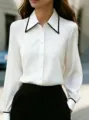 Detail view of a chic white long sleeve blouse featuring a contrast black lapel and button front. - S / White