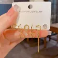Detailaufnahme des goldenen Ohrring-Sets mit geometrischen Herz- und Quastenanhängern. - Metall Pfeil Herz Quasten-Set (54#) / Gold
