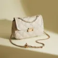 Elegante borsa a tracolla in pelle trapuntata beige con catena dorata e serratura in metallo. - Bianco