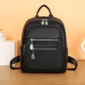 Detail view of black leather women backpack with multiple zippers and stylish metal pendants. - Black