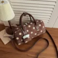 Detailed view of brown polka dot handbag showing soft suede and stylish metal chain charm. - Coffee