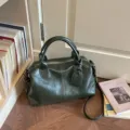 Gedetailleerd overzicht van donkergroene vintage Boston handtas met handvatten en riem. - Eén maat / Groen