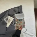 Detailansicht der grauen bestickten Mini Umhängetasche für Handys mit Quasten-Anhänger. - Silber
