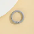 Gedetailleerd overzicht van grijze ronde veerring, zinklegering karabijnhaak op beige. - Grijs