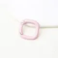 Gedetailleerde close-up van een lichtroze vierkante metalen veergesp voor knutselaccessoires. - Roze vierkante veergesp