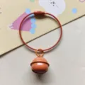 Detailopname van de oranje gelakte bel metalen sleutelhanger met staalkabel. Mooie tasbedel. - Oranje staaldraad ring + 22 mm belletje