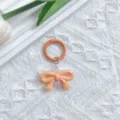 Detailed shot of electroplated UV orange bow keychain, cute bag charm with spring ring. - Orange Bowknot & Spring Ring Clasp