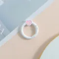 Vista detallada de anillo de resorte blanco con dije de esmalte de corazón rosa para manual. - Blanco