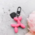 Roze ballon hond sleutelhanger met zwarte metalen sluiting en schattige hartjes hanger. - Mat rozerode ballonhond met zwarte karabijnhaak