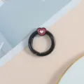 Primer plano detallado del cierre de anillo de resorte de metal negro con un dije de corazón rosa. - Negro