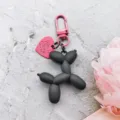 Detailed close-up of a cute black balloon dog keychain with pink heart charm and metal hook. - Matte Black Balloon Dog with Rose Red Carabiner