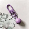 Primo piano dettagliato di un moschettone in metallo viola con ciondolo a campanella laccata. - Viola