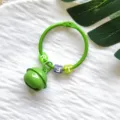 Close-up van groene metalen ring sleutelhanger met kleine bel en letterkralen. - Kaartring Bel Bedel / Groen