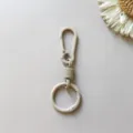 Detailed shot of beige zinc alloy spring keychain carabiner, smooth metal clasp texture. - Light Coffee Hanging Clasp