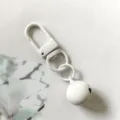 Dettaglio portachiavi in metallo bianco con moschettone e campanella per accessori borse fai da te. - Bianco