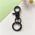 Dettaglio moschettone girevole in metallo nero, anello a molla portachiavi accessorio borsa DIY primo piano - Moschettone nero e anello a molla da 24 mm