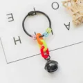Detailed view of DIY keyring pendant with black metal ring, colorful links and small bell. - Black
