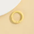 Close-up van een kleine gele ronde veerring, detailopname van metalen doe-het-zelf accessoire. - Lichtgeel