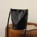 Black leather bucket bag with adjustable strap and vintage brass hardware, stylish and spacious. - Starry Black