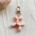 Cute pink balloon dog keychain charm with gold metal clasp for stylish bags and keys. - Pink