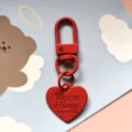 Detailopname van rode metalen hart sleutelhanger met karabijnhaak en gegraveerde tekst. - Rood