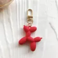 Detailopname van de schattige rode ballonhond sleutelhanger bedel met glanzende gouden hardware. - Rood