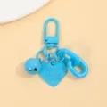 Détail en gros plan du porte-clés cœur en alliage bleu vif avec cloche et chaîne. - Bleu