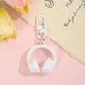Close-up van een witte 3D koptelefoon sleutelhanger, leuk tasaccessoire op roze achtergrond. - Koptelefoon met Gesp / Wit