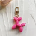 Close-up detail view of the vibrant pink rubber balloon dog keychain pendant and golden clasp. - Rose Red