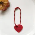 Rood hart kralenketting hanger detailopname, minimalistische DIY-accessoire voor tassen. - Rode hartbedel met 12 mm ballketting