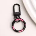 Gedetailleerd overzicht van de zwarte legering donut sleutelhangerring met roze stippen. - Zwarte donut veerringslot en karabijnsluiting