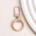 Detailopname van de metalen legering donut veer sleutelhanger sluiting met kleurrijke afwerking. - Lichtbruine donut veerringslot en karabijnsluiting