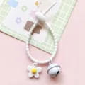 Detailed view of white silicone strap keychain featuring a cute daisy flower and bell. - Cable Tie Bell Flower / White