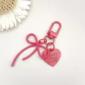 Roze legering strik hart hanger sleutelhanger detailopname, perfect doe-het-zelf accessoire. - Rode veersluiting met legering strik en hartbedeltje