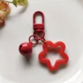 Gedetailleerde close-up van rode acryl sterhanger met kleine bel en karabijnhaak. - Rode veersluiting met 14 mm belletje en ster