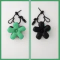 Gedetailleerd overzicht van de schattige puffer bloem tasbedel met zwarte ketting. - Groene en zwarte patchwork bloem met zwart koord