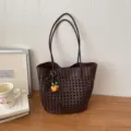Nahaufnahme der dunkelbraunen geflochtenen Ledertasche mit feinem Lochmuster und Anhänger. - Mit Anhänger / Braun