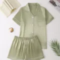 Close-up detail of green satin silk-like pajama set, short sleeve top and shorts flat lay. - Light Green